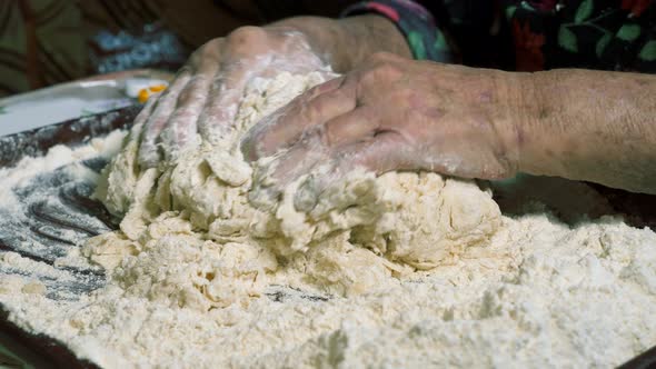 Wrinkled Hands of an Elderly Man Knead the Dough and Make Balls of Kolobok