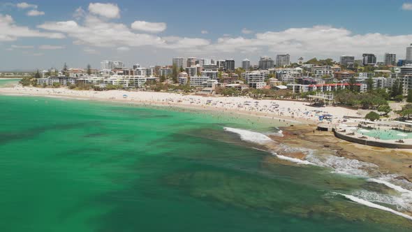 Aerial drone footage of ocean waves on a busy Kings beach, Caloundra, Australia