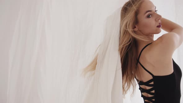 Sensual Young Girl Posing in the Studio Doing Dance Moves with Pieces of White Tulle in Her Hands