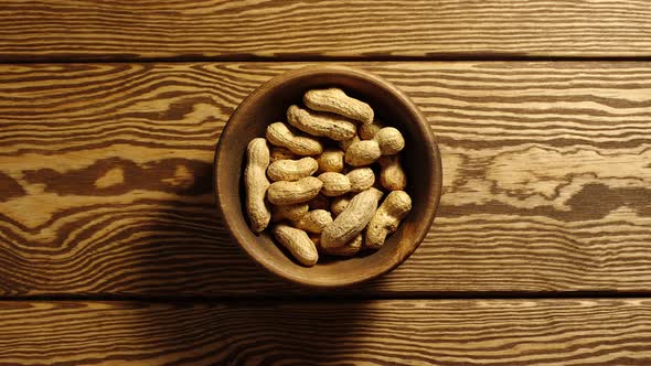 Unpeeled peanuts appear in wooden cup and full this cup