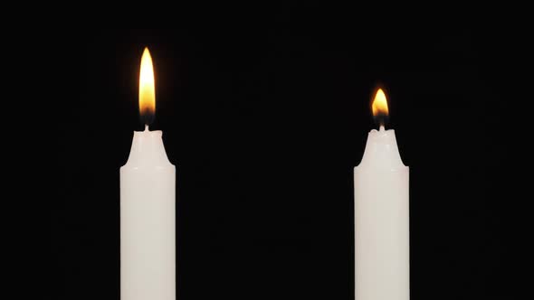 Two Candles Are Burning on a Black Background Nearby