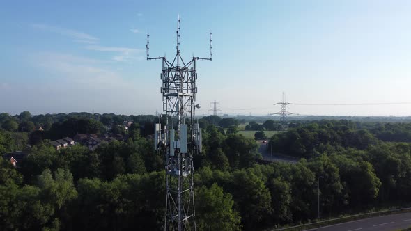 5G broadcasting tower antenna in British countryside woodland with vehicles travelling on highway ba