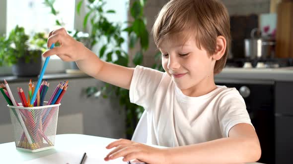 Cute Smiling Boy Draws with Colored Pencils at Home at the Table Happy Baby