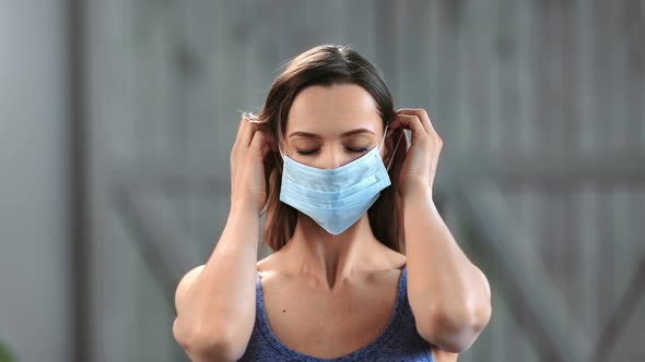 Portrait of Confident Young Blonde Woman Putting on Medical Mask