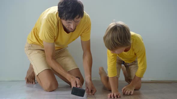 Father and His Little Son Install Laminate on the Floor in Their Apartment