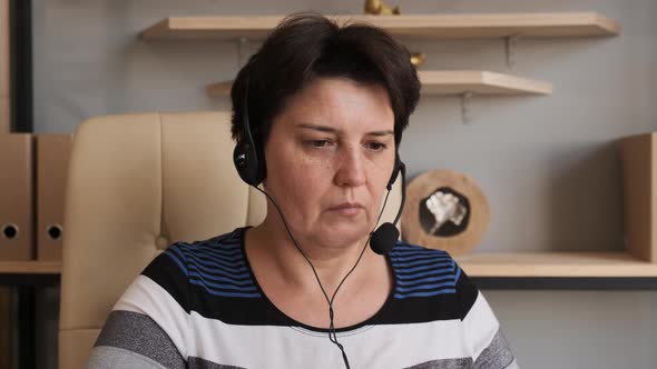 Woman Wear Headset Communicating By Conference Call Speak Looking at Computer at Home Office