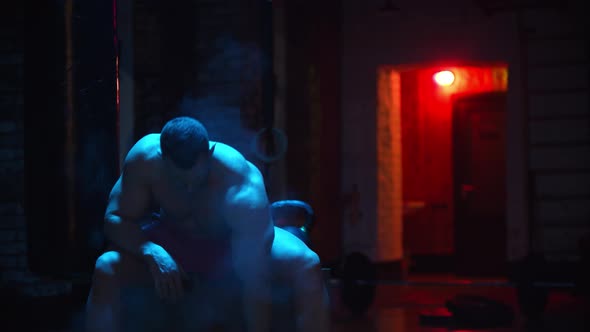 Tough Man Clapping His Hands Covered in Chalk and Pumping His Biceps in Contrast Lighting