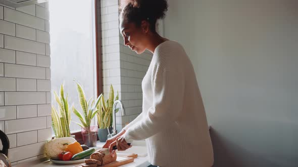 Side view of African concentrated pregnant woman cuts bread