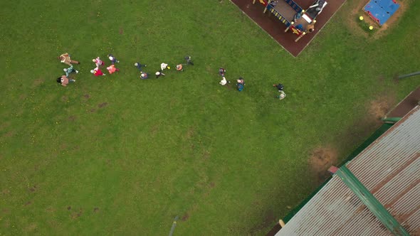 Children in Kindergarten Go in a Row on a Green Lawn
