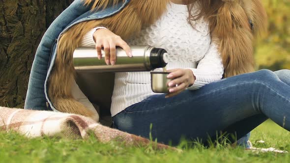 Girl Pouring Tea From Thermos, Enjoying Hot Drink in Autumn Forest, Comfort