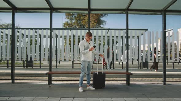 A Man is Standing at a Public Transport Stop