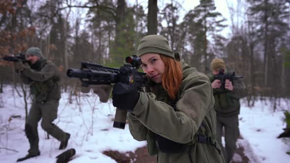 Beautiful Young Caucasian Woman in Camouflage with Strikeball Gun Walking in Slow Motion Aiming As