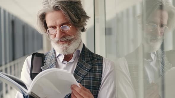 Mature Businessman in Suit Reading in the Airport Terminal