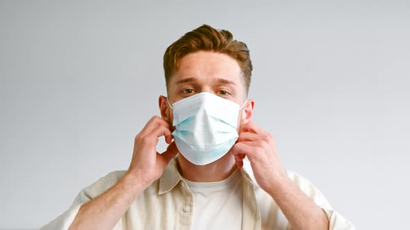 Bearded company manager in yellow shirt takes off blue face mask