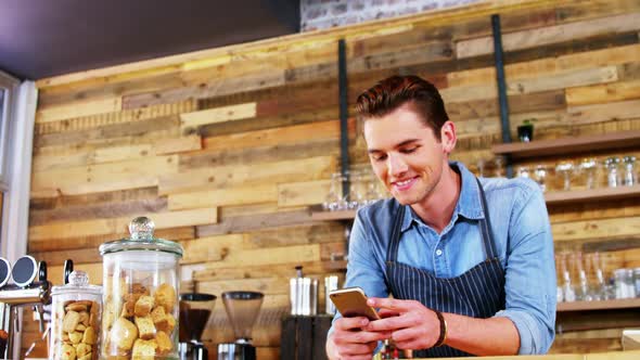 Male waiter using mobile phone at counter