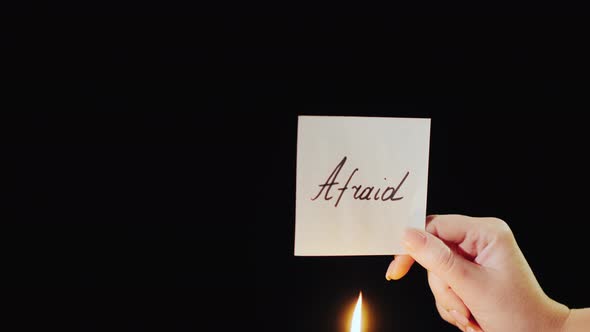 Man Burns a Paper with the Inscription Afraid