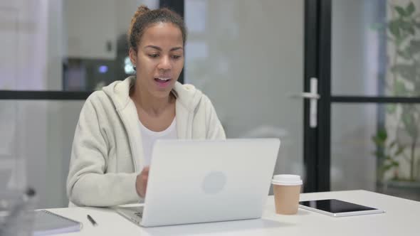 African Woman Celebrating Success While Using Laptop in Office