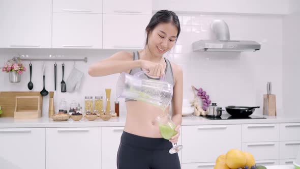 Asian woman drinking apple juice in the kitchen use organic fruits