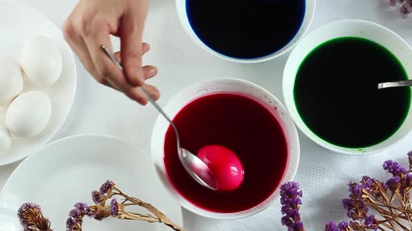 A Man Paints Easter Eggs in White Plates in Multicolored Colors Minimalist