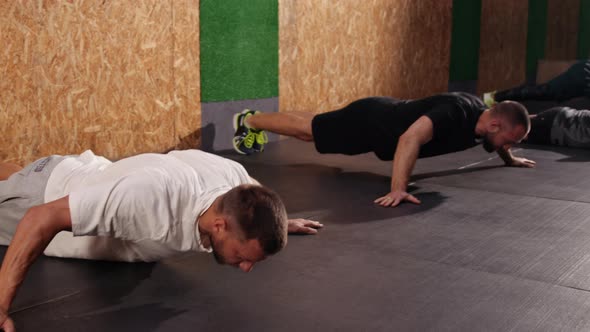 Strong Fit Athletic Men Doing Push Up Exercises in a Loft Style Industrial Gym