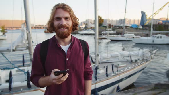 Smiling Man with Smartphone near River