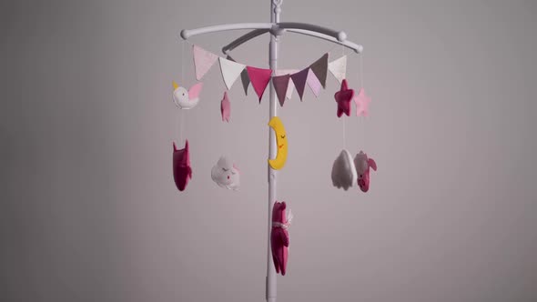 Baby Mobile with Pink Handstitched Animal and Bird Toys with Yellow Moon on White Wall Background