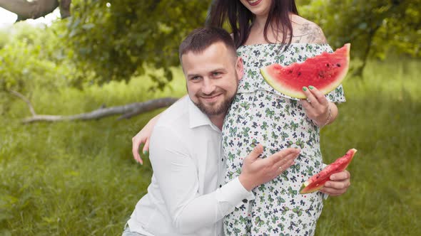 Happy Married Couple with Watermelon in Hands Posing at Green Garden