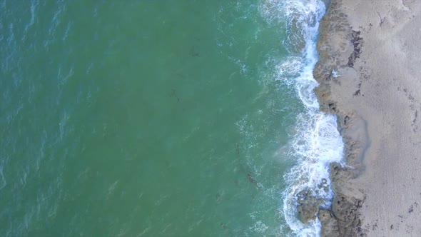 A straight down shot of surf crashing onto the beach.