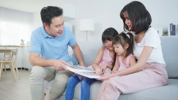 Asian family look at photographs on old picture album recalls the past.