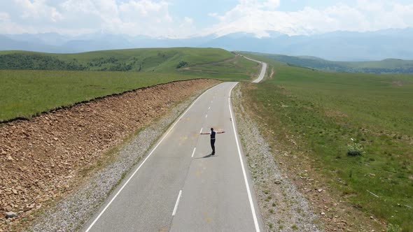 Guy in Summer in Black Clothes Descends From the Mountain on a Skateboard