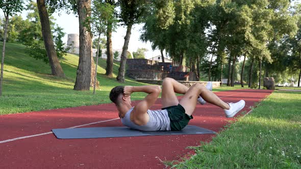 Athlete Guy Doing Bicycle Exercise for Abs Muscles Outdoor Training