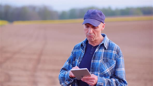 Farmer Examining Agricultural Field While Working on Digital Tablet Computer at Farm