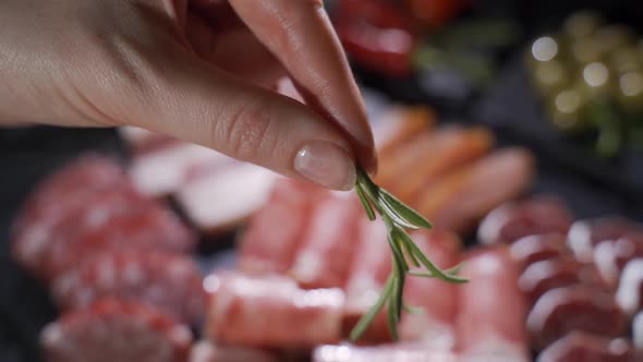 Chef Decorates with a Sprig of Rosemary a Plate with Chopped Meat Delicacies