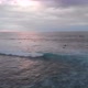 Aerial flyover view of waves crashing during sunset with people swimming in the sea in Bali - VideoHive Item for Sale