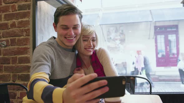 Video call. Happy couple in cafe using phone for video chat