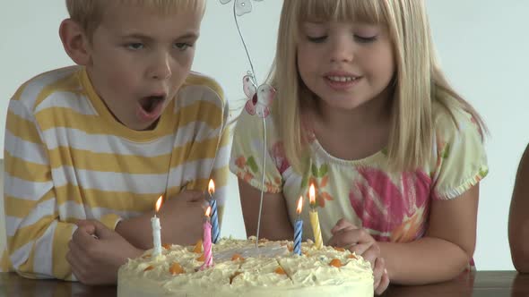 CU OF A BROTHER AND SISTER BLOWING OUT CANDLES ON A BIRTHDAY CAKE