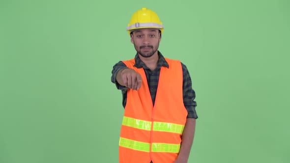 Happy Young Bearded Persian Man Construction Worker Pointing at Camera