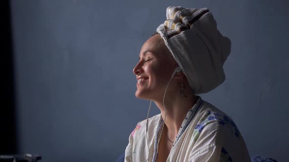 Happy Woman Enjoy Music in Headphones Sit on Bed Wear Towel and Bathrobe and Drink Coffee Akspb