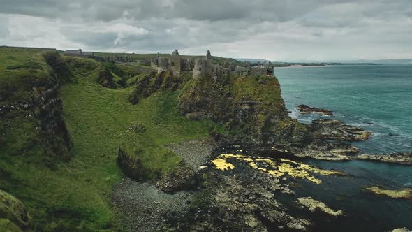 Irish Castle Cliff Shore Aerial View Dunluce on Green Grass Valleys and Meadows at Ocean Bay