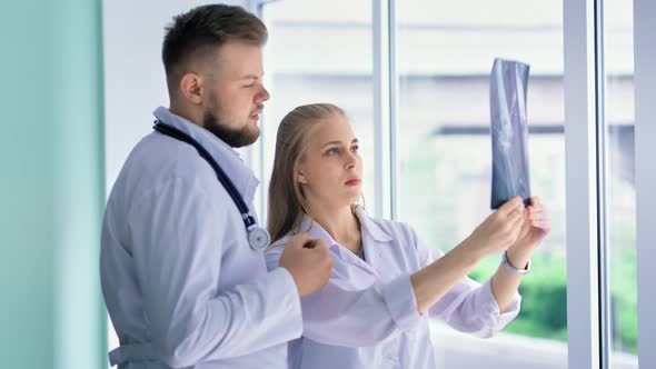 Female and Male Doctor in White Coat Reviewing Xray Pointing on Snapshot