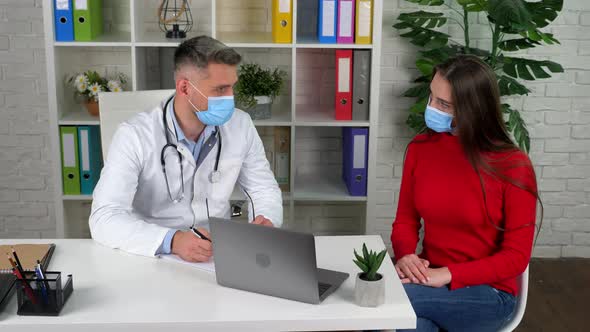 Doctor and patient wears protective masks on faces in hospital communicates talk