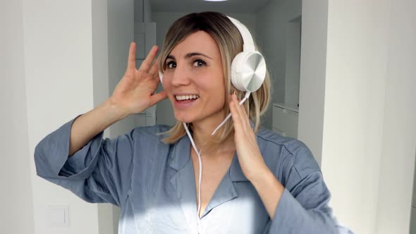 Portrait of cheerful european woman in headphones listening to music