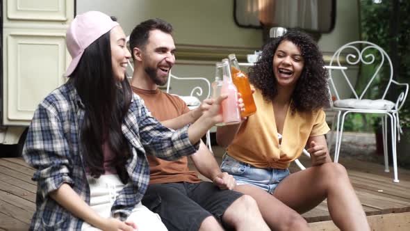 Beautiful people toasting with drinks at the party. Multiethnic friends clinking with beer bottles