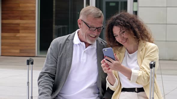 Beautiful Mature Couple with Suitcases is Sitting on a Bench Waiting for Their Flight