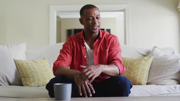 Happy biracial man sitting on sofa and having video call