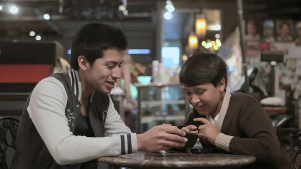 Two brothers with smartphone in cafe