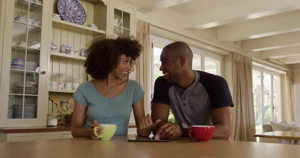 Happy mixed race couple drinking coffee in their kitchen