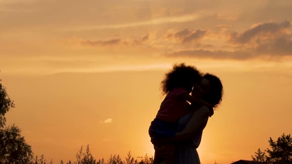 Silhouettes of Mother and Daughter Hugging Against Beautiful Evening Sky, Love