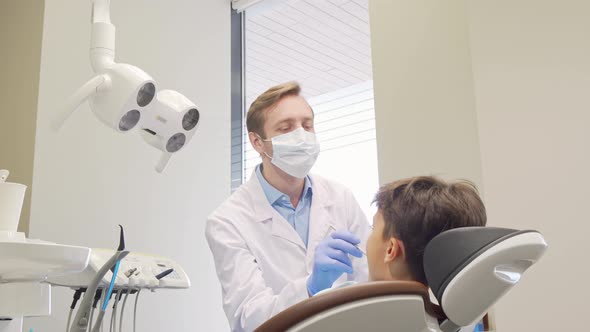 Mature Dentist High Fiving His Little Patient After Checking His Teeth