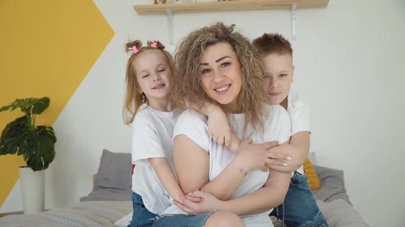 Mom with Daughter and Son Hug Sitting in a Cozy Room